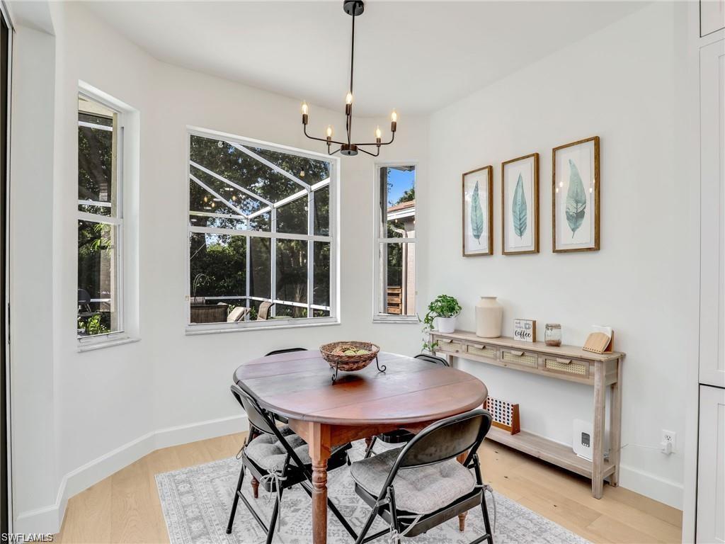Dining room featuring healthy amount of natural light, light wood-style flooring, and a chandelier