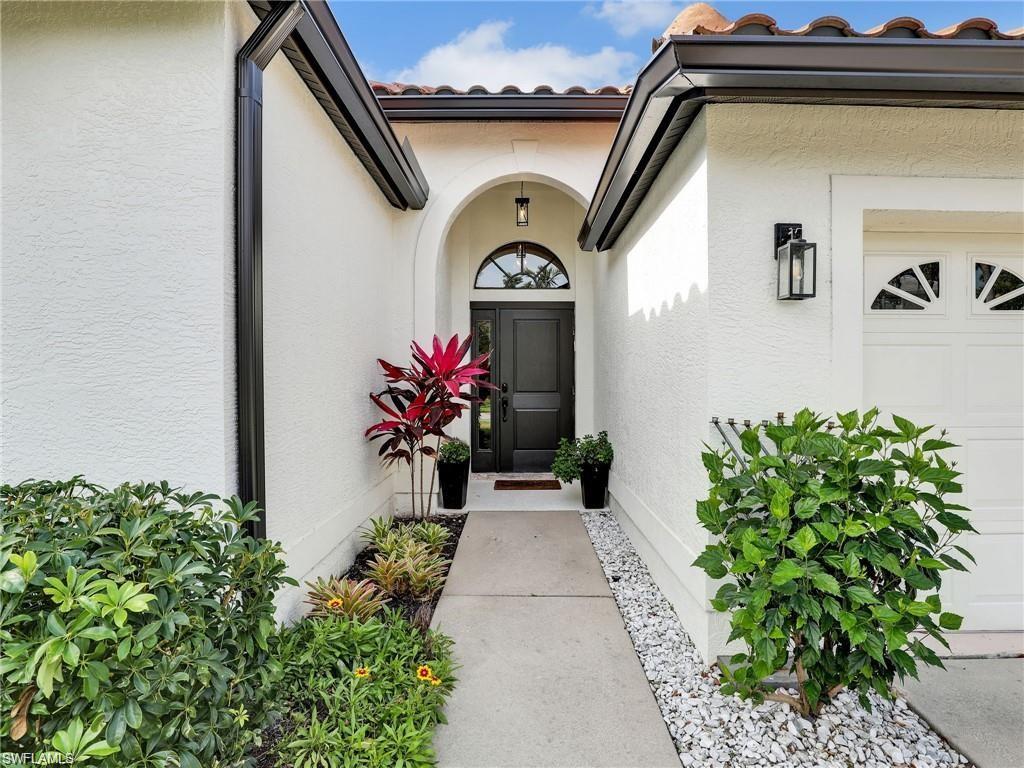 Entrance to property featuring a tiled roof, stucco siding, and a garage