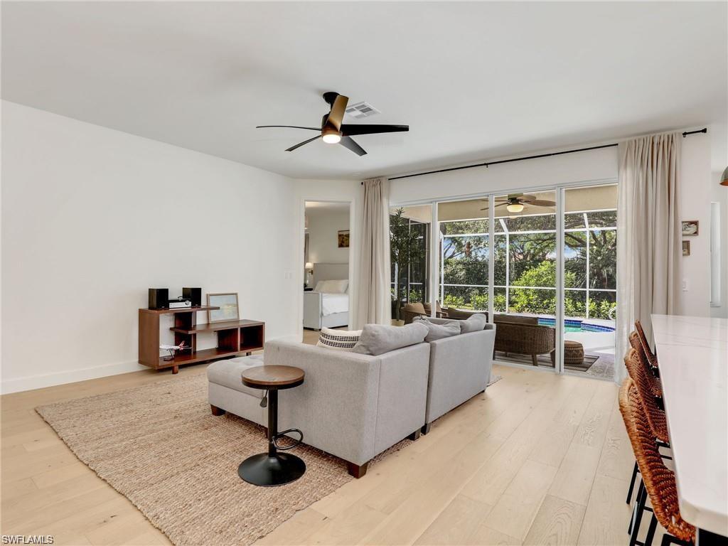 Living area featuring light wood-style floors, ceiling fan, and a sunroom