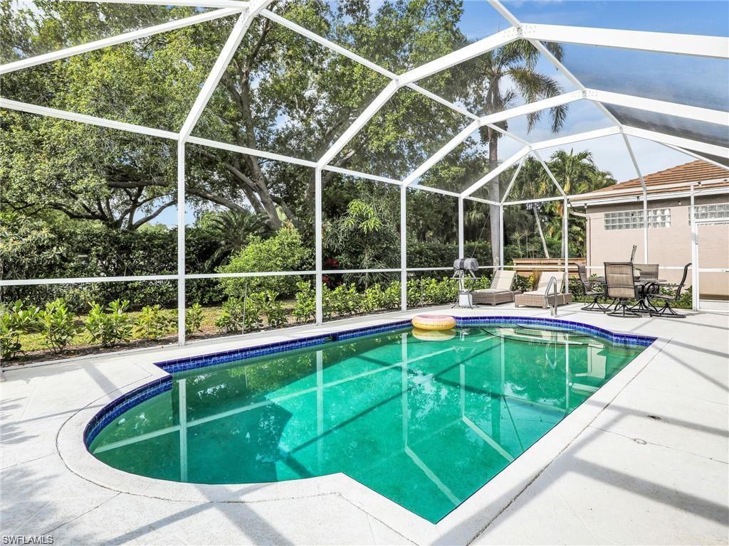 Outdoor pool with a lanai, a patio, a sunroom, and view of wooded area