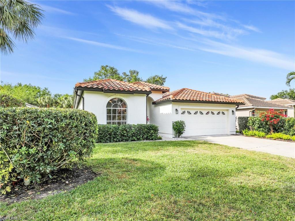 Mediterranean / spanish house with stucco siding, a garage, driveway, a front lawn, and a tile roof