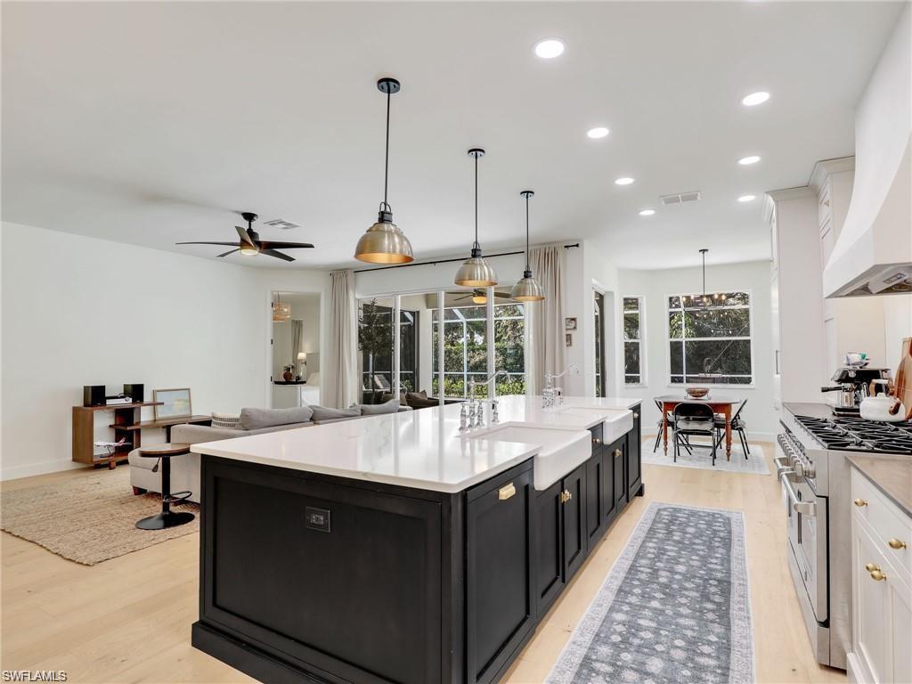 Kitchen with dark cabinets, hanging light fixtures, range with two ovens, recessed lighting, and white cabinetry