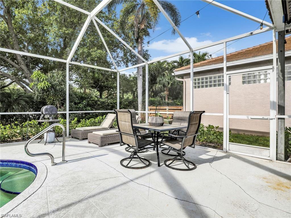 View of patio / terrace with a sunroom, a lanai, outdoor dining area, and an outdoor pool