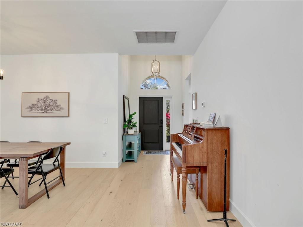 Entryway featuring light wood-style floors, a chandelier, and a towering ceiling