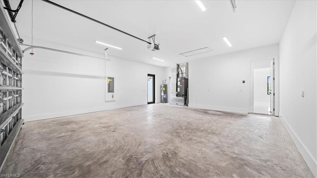 Garage featuring heating unit, water heater, and electric panel