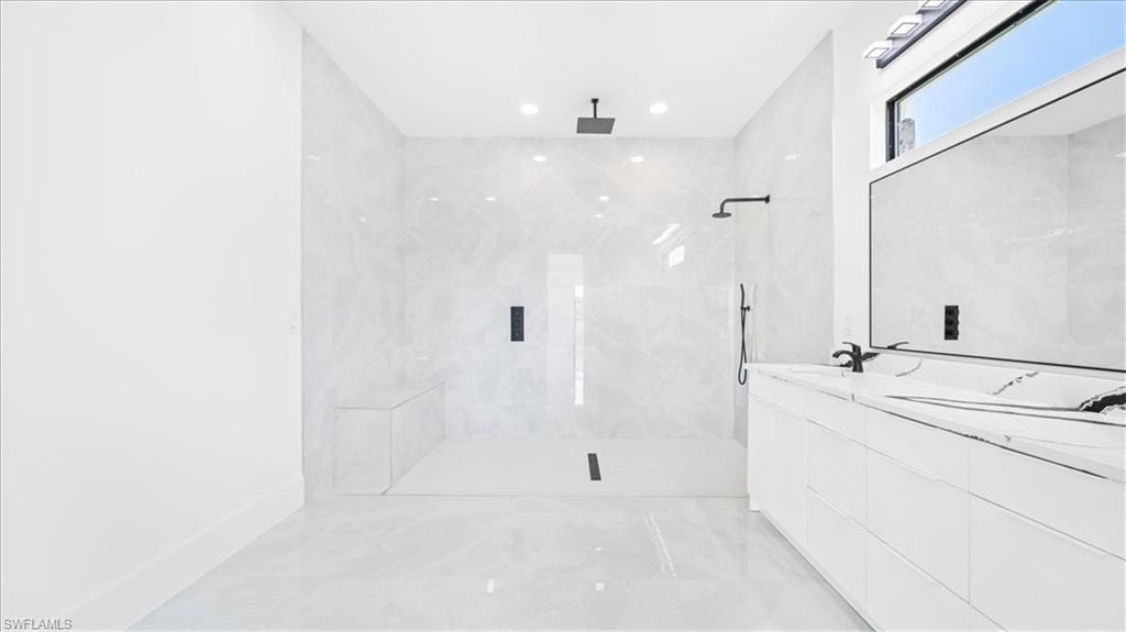 Full bathroom featuring double vanity, light marble finish floors, a marble finish shower, and recessed lighting