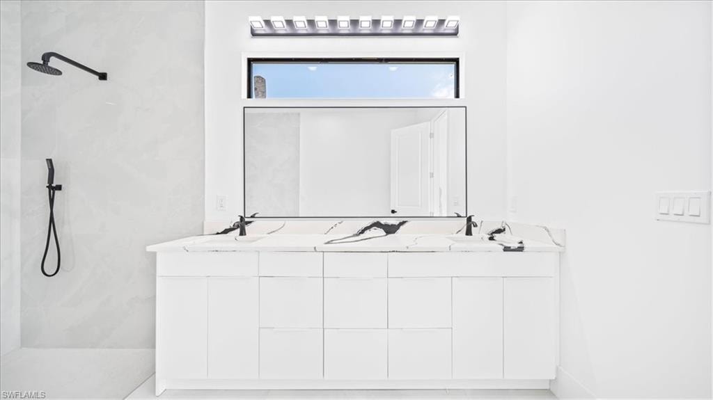 Bathroom featuring double vanity and a marble finish shower