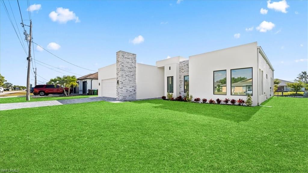 Contemporary home featuring a front lawn, driveway, and stucco siding