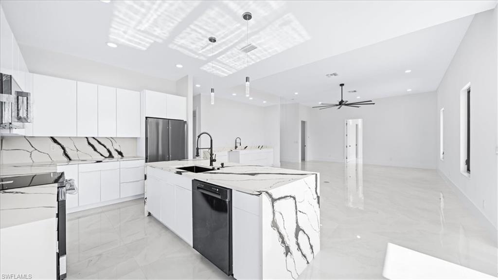 Kitchen with white cabinetry, modern cabinets, stainless steel appliances, a ceiling fan, and light stone counters