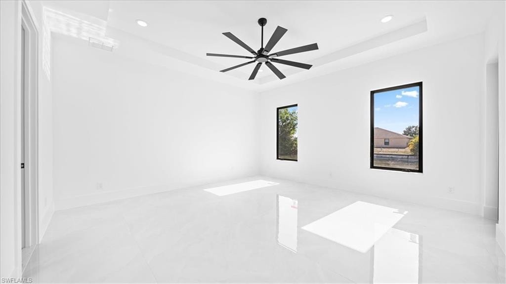 Unfurnished room featuring a tray ceiling, recessed lighting, and ceiling fan