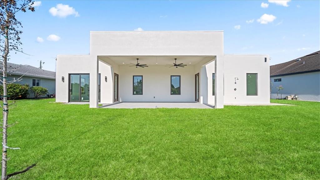 Back of property with a patio, stucco siding, ceiling fan, and a yard