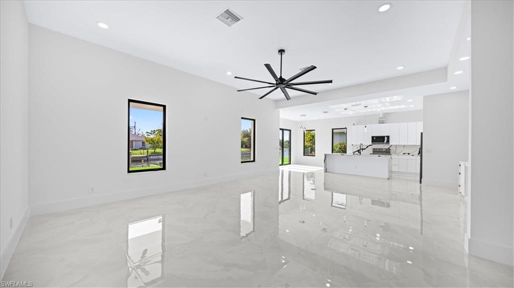 Unfurnished living room featuring plenty of natural light, recessed lighting, ceiling fan, and light marble finish flooring