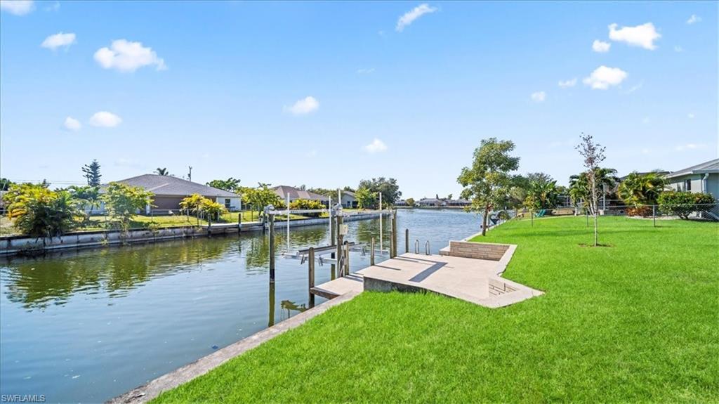 Dock featuring a water view, boat lift, a yard, and a residential view