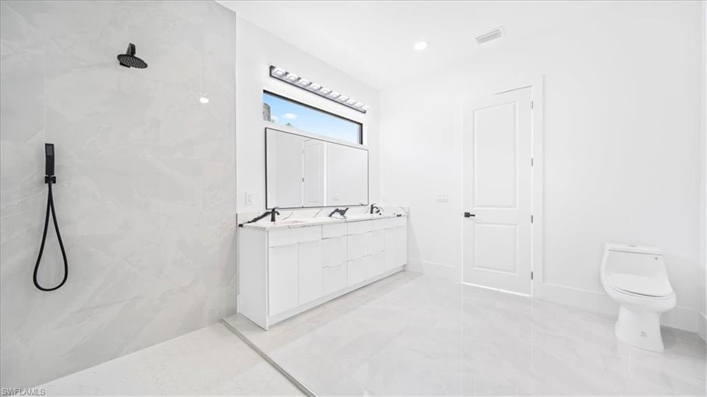 Bathroom featuring a marble finish shower and double vanity