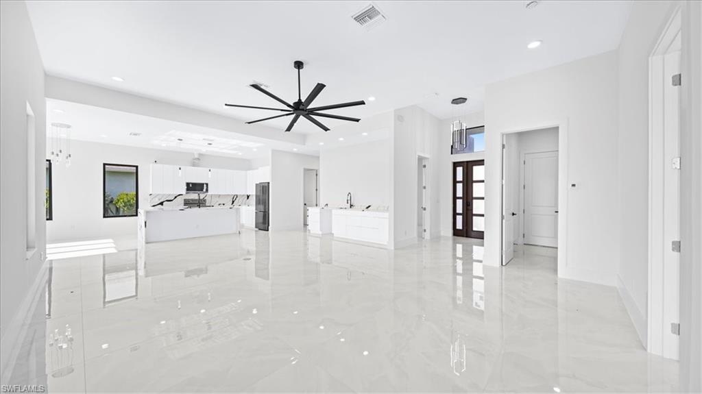 Unfurnished living room with light marble finish flooring, french doors, recessed lighting, and ceiling fan