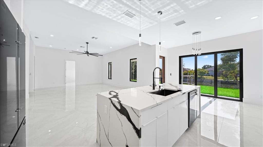 Kitchen featuring modern cabinets, white cabinets, recessed lighting, pendant lighting, and light stone counters