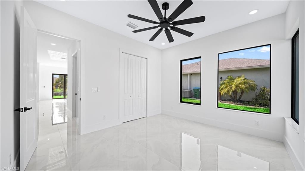 Unfurnished bedroom featuring light marble finish floors, a ceiling fan, a closet, and recessed lighting
