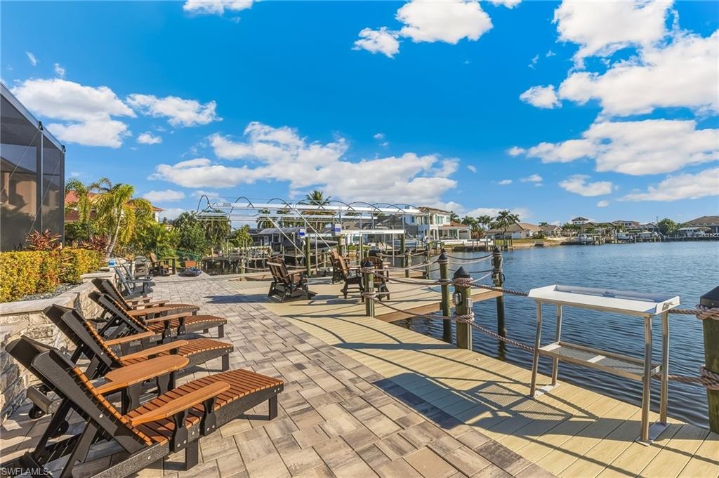 Dock area with a water view, boat lift, a residential view, a lanai, and a sunroom