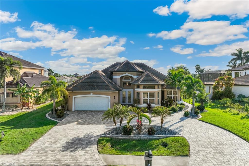 View of front facade with french doors, stucco siding, a front lawn, and decorative driveway
