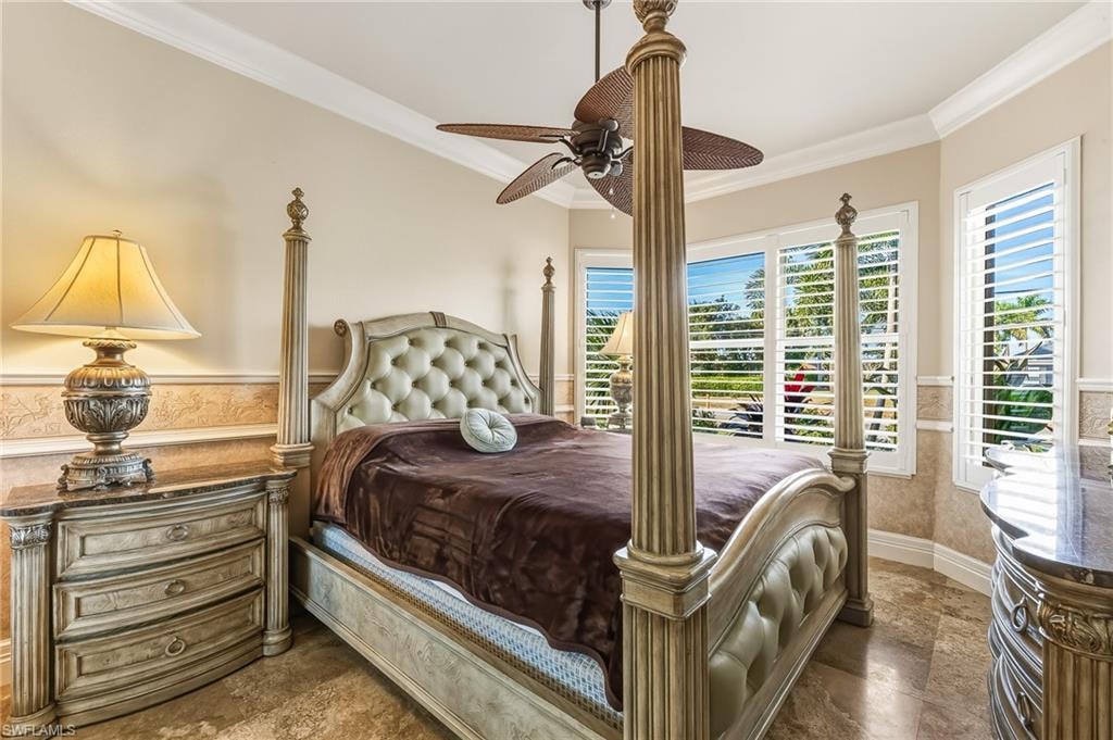 Bedroom featuring ornamental molding, a wainscoted wall, and a ceiling fan
