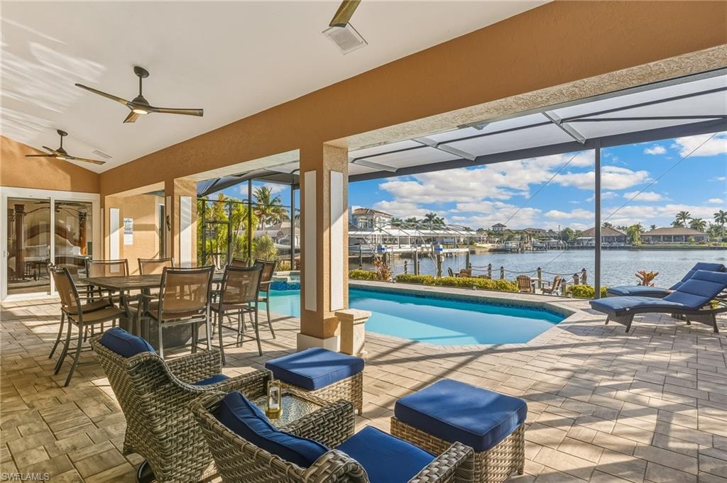 Outdoor pool with a lanai, a patio area, a water view, boat lift, and outdoor dining area