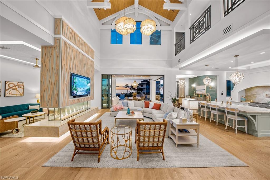 Living area with a chandelier, beamed ceiling, light wood-style floors, and high vaulted ceiling