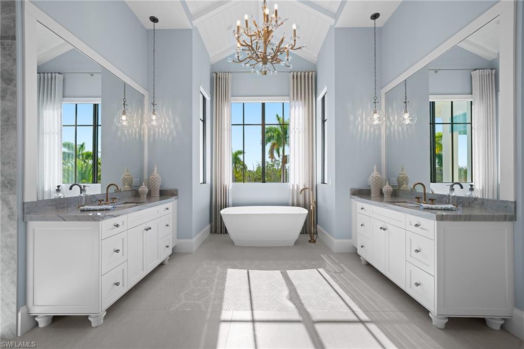 Full bathroom with wooden ceiling, a chandelier, two vanities, a freestanding bath, and healthy amount of natural light