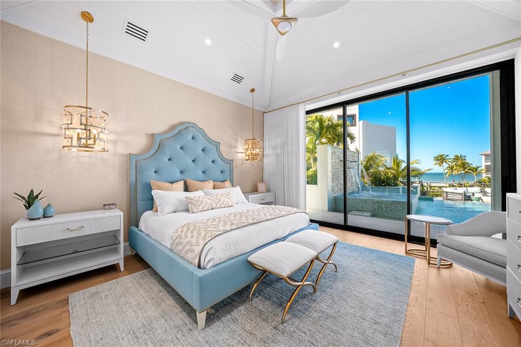 Bedroom featuring hardwood / wood-style flooring, access to exterior, a chandelier, and a water view