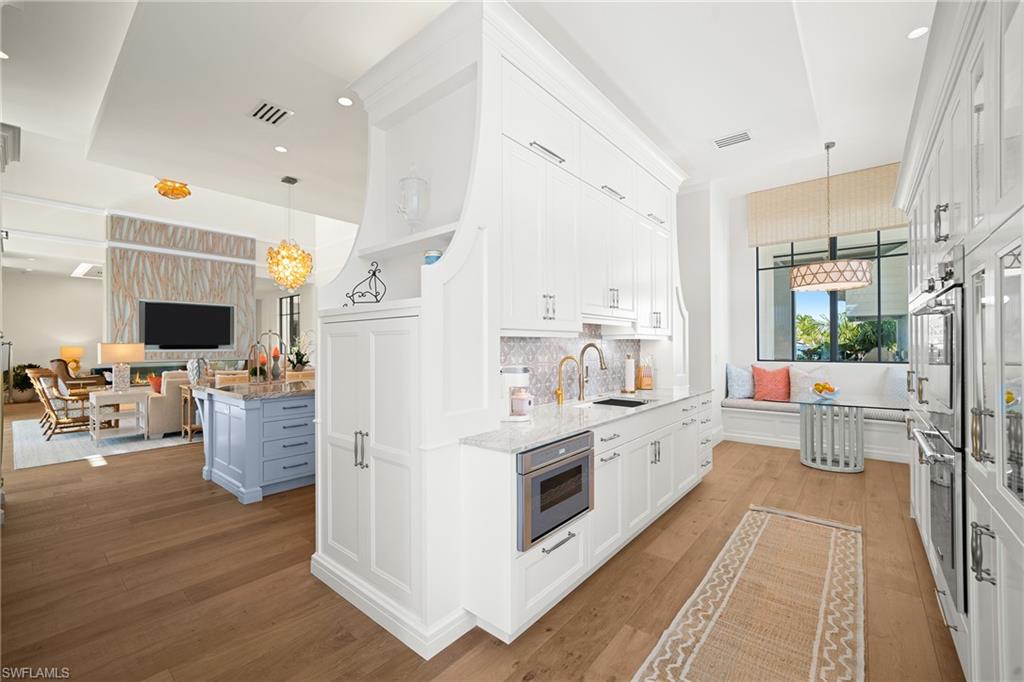 Kitchen with hanging light fixtures, white cabinets, light stone countertops, open floor plan, and recessed lighting