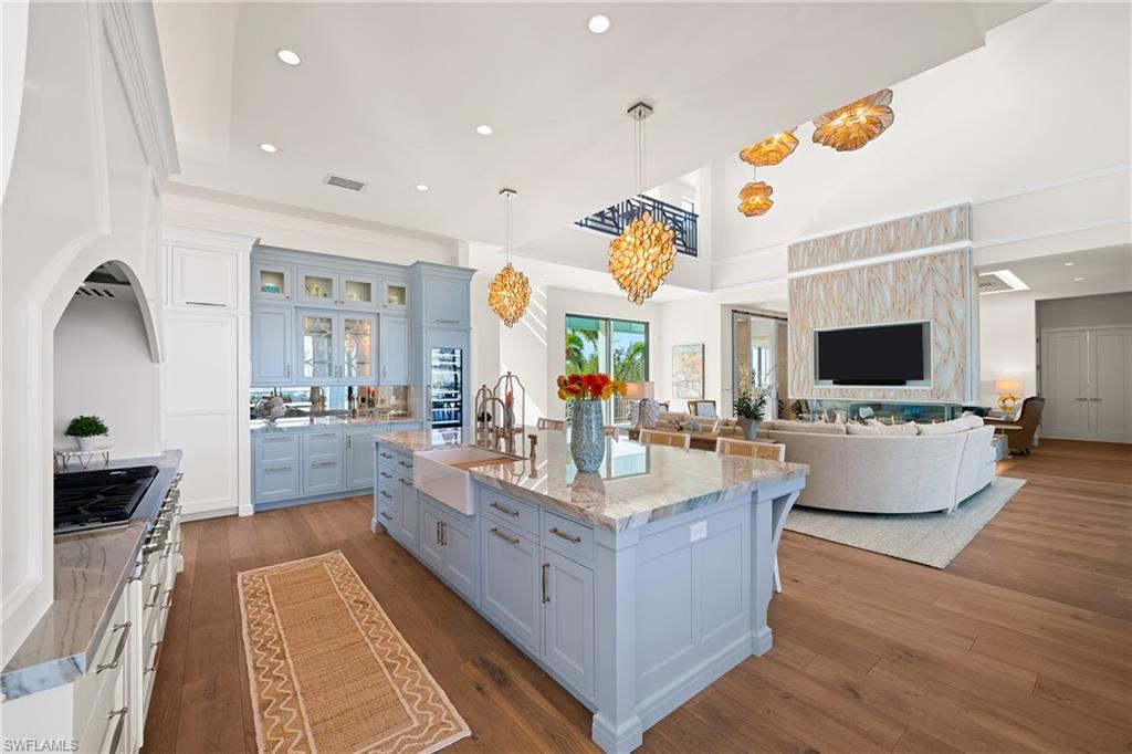 Kitchen with recessed lighting, glass insert cabinets, decorative light fixtures, open floor plan, and dark wood finished floors