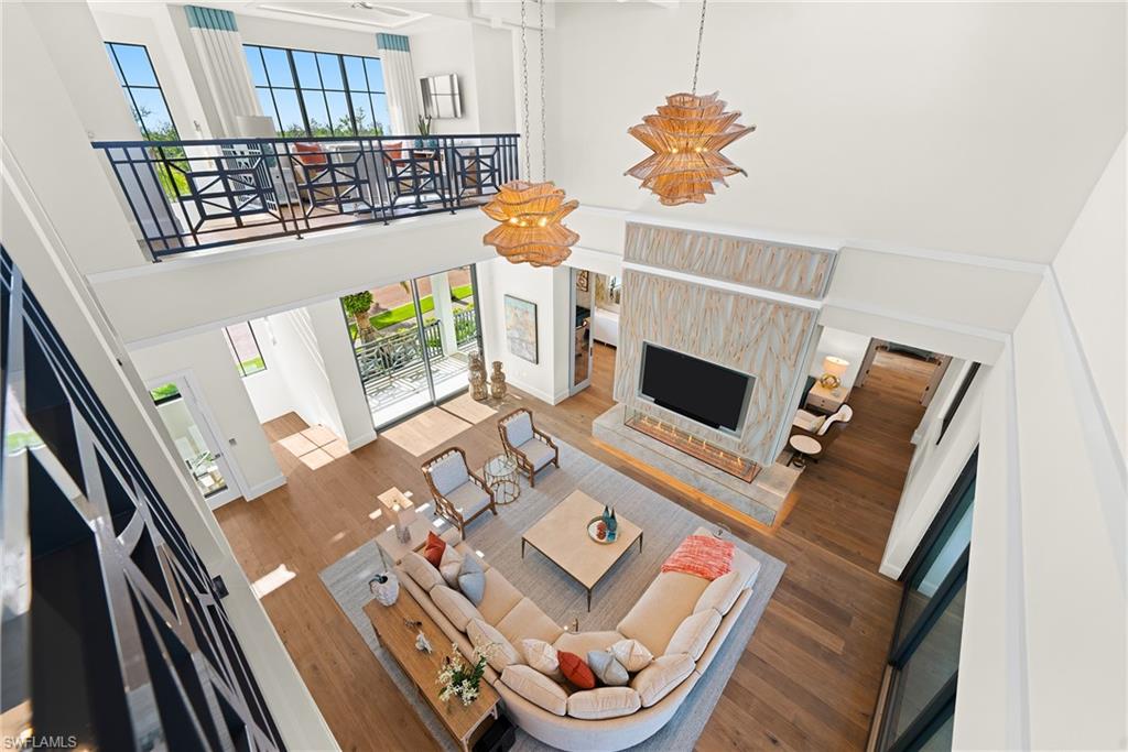 Living area with a towering ceiling, healthy amount of natural light, wood finished floors, and a premium fireplace