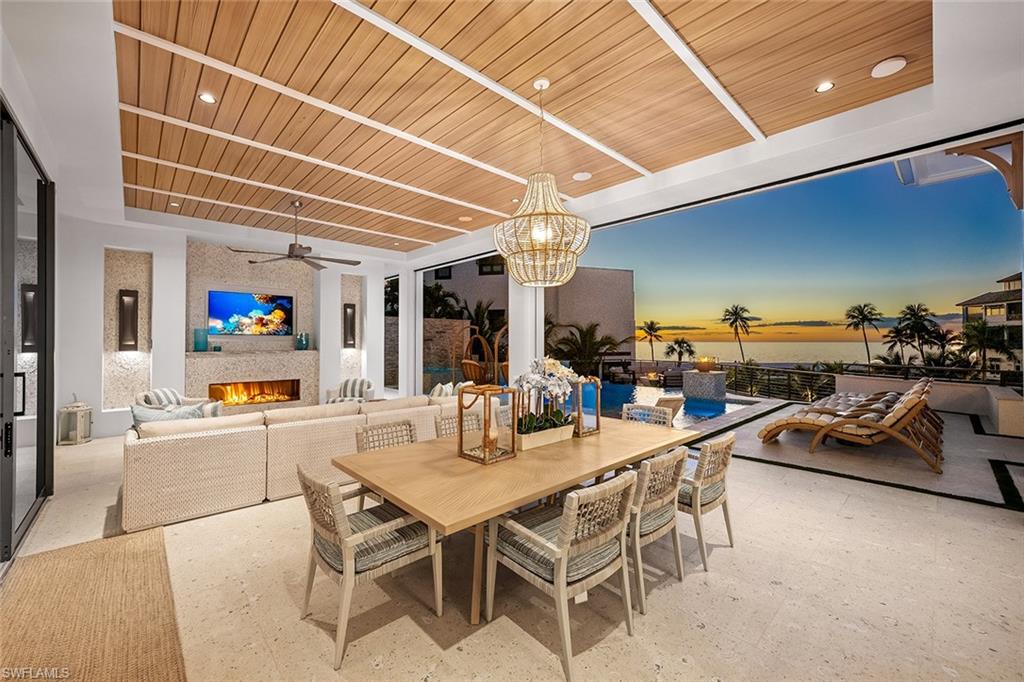 Dining area featuring a large fireplace, wood ceiling, recessed lighting, a chandelier, and ceiling fan