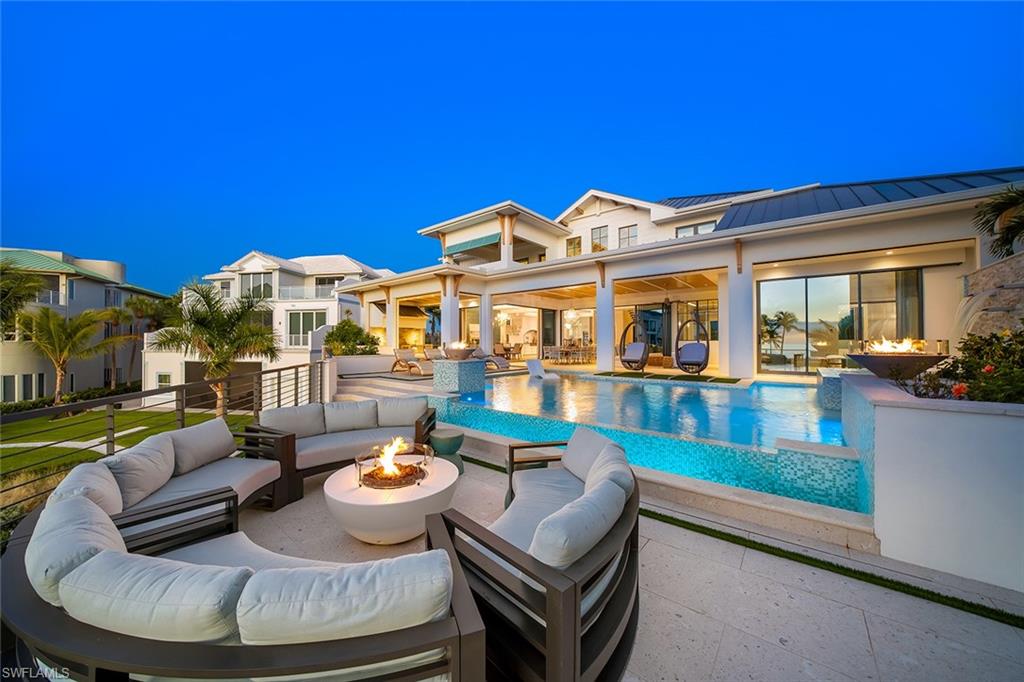 View of swimming pool with a patio, an infinity pool, and an outdoor living space with a fire pit
