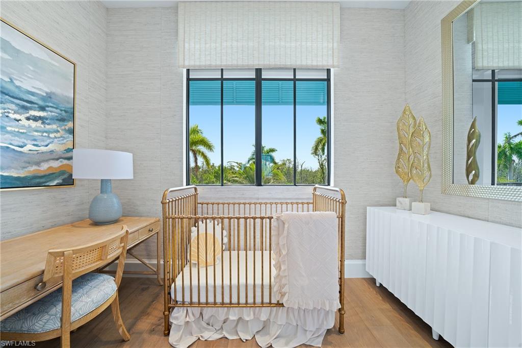 Bedroom with radiator heating unit, a nursery area, and wood finished floors