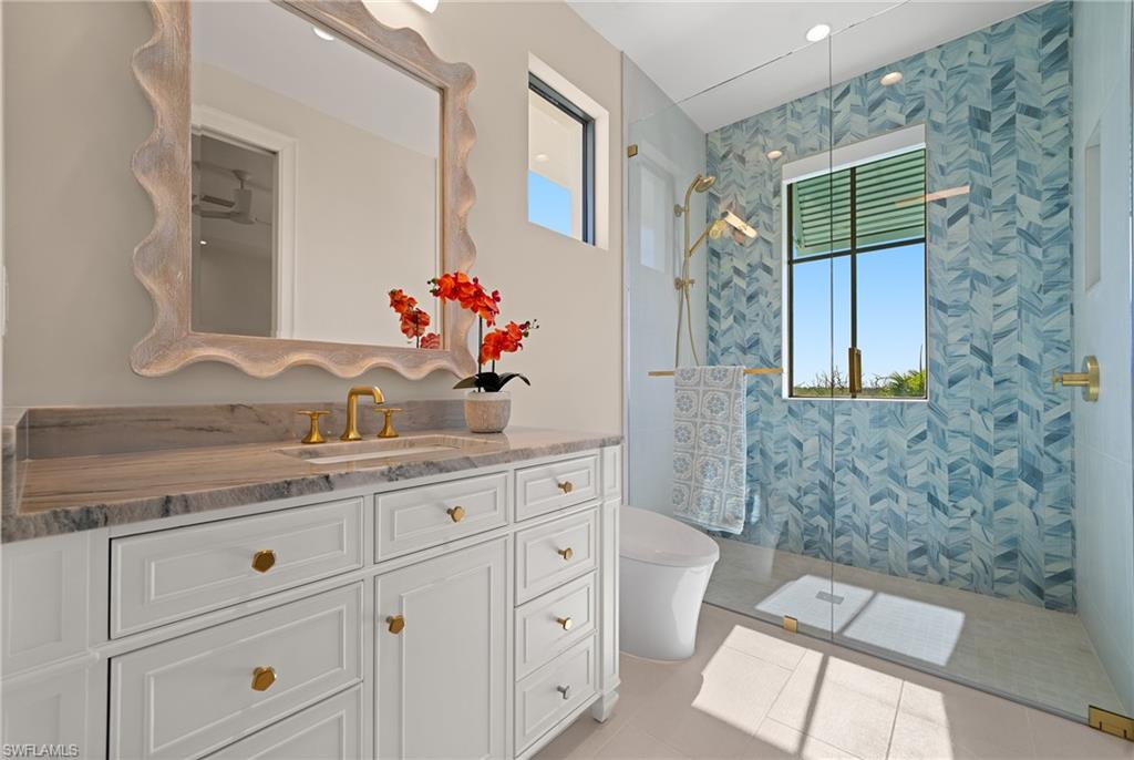 Full bath with walk in shower, vanity, and light tile patterned floors