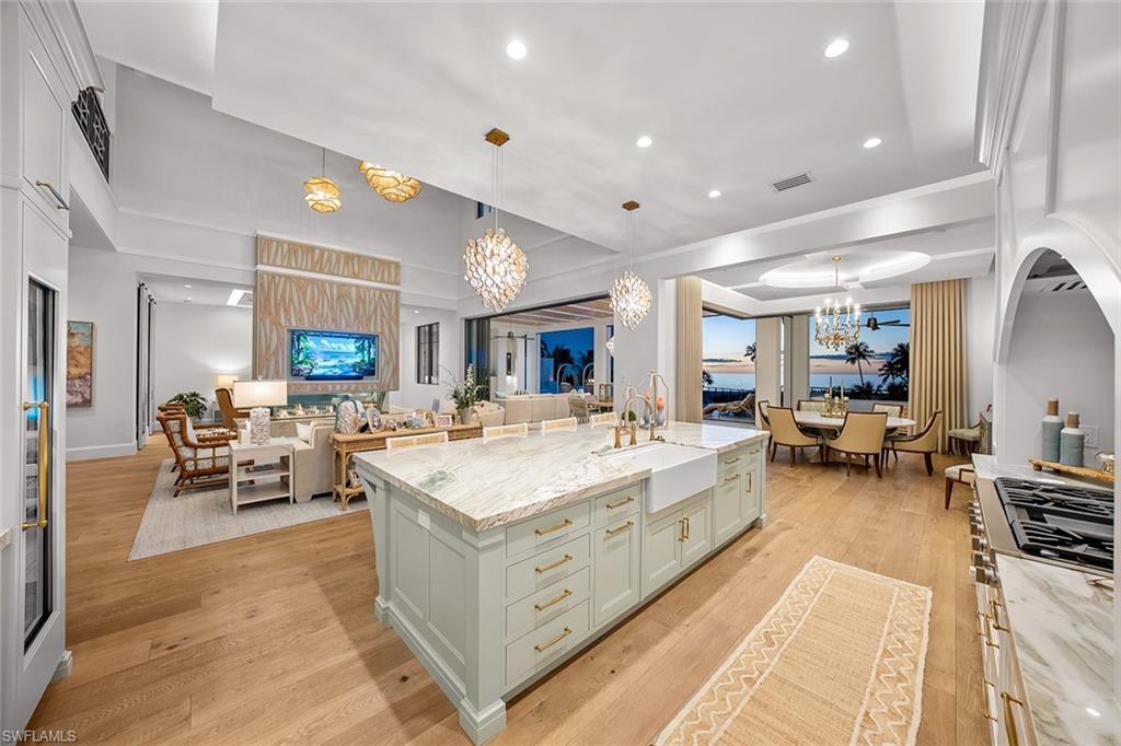 Kitchen featuring light stone countertops, open floor plan, a chandelier, pendant lighting, and recessed lighting