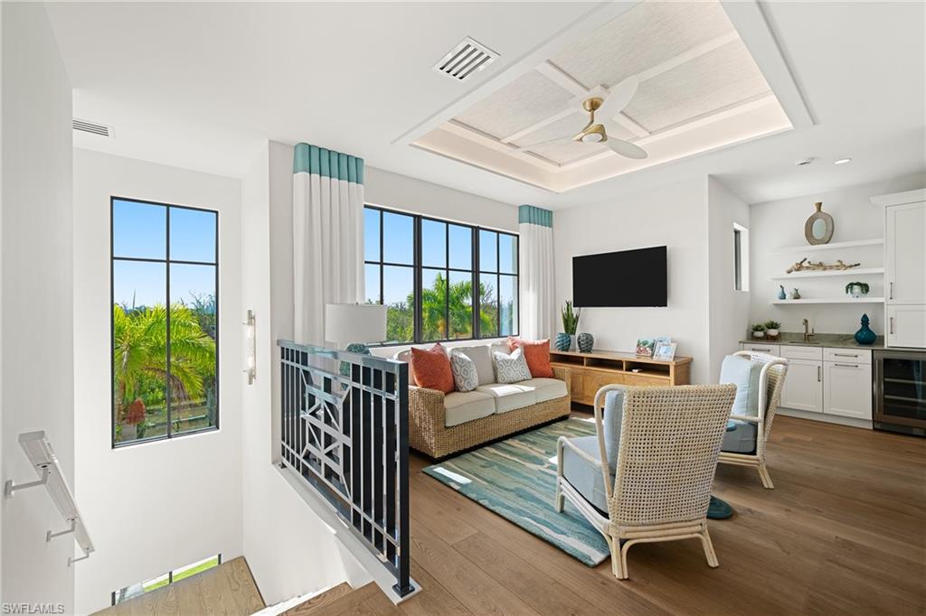 Living room with beverage cooler, wet bar, wood-type flooring, and a ceiling fan
