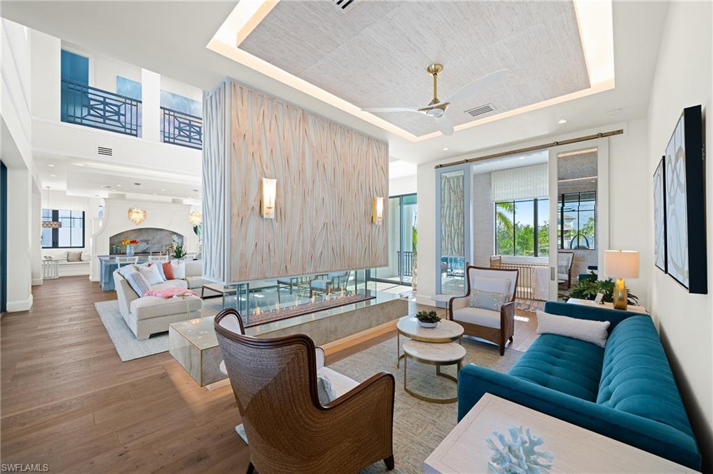 Living room with a raised ceiling, ceiling fan, hardwood / wood-style floors, and recessed lighting