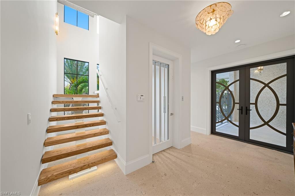 Foyer entrance featuring healthy amount of natural light, french doors, and stairs