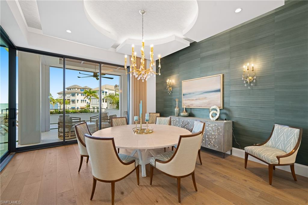 Dining room with an accent wall, wood-type flooring, ceiling fan, wallpapered walls, and a chandelier