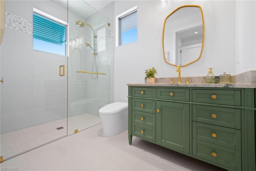 Full bath featuring vanity, a walk in shower, plenty of natural light, and light tile patterned flooring