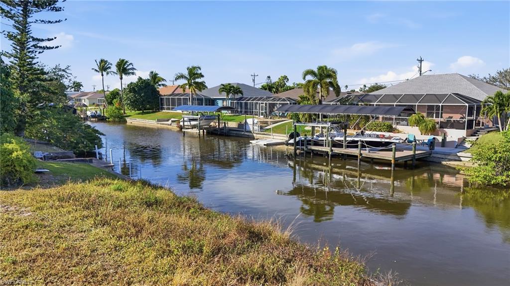 Dock featuring a water view, a residential view, boat lift, a sunroom, and a lanai