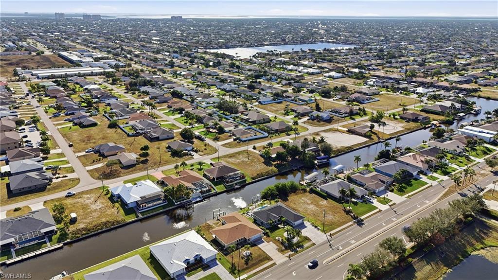 Aerial view of property and surrounding area featuring a nearby body of water and nearby suburban area
