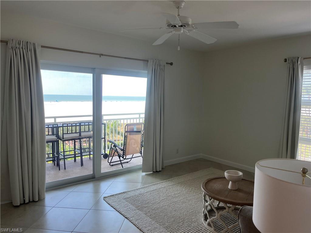 Unfurnished room with healthy amount of natural light, light tile patterned floors, a water view, and a ceiling fan