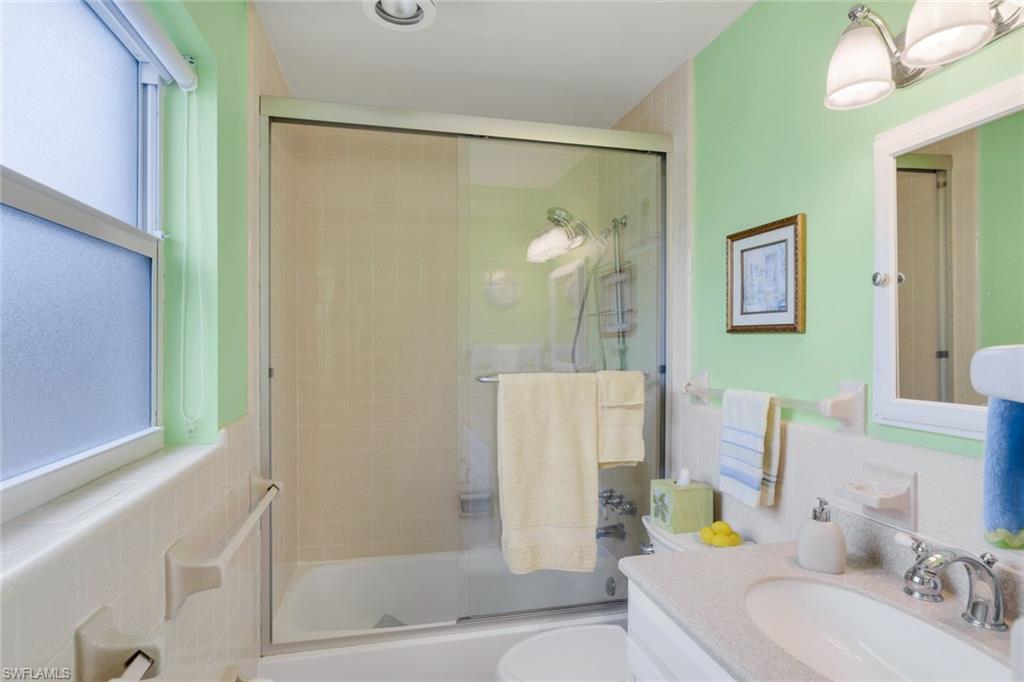 Full bathroom featuring bath / shower combo with glass door, tile walls, backsplash, vanity, and toilet