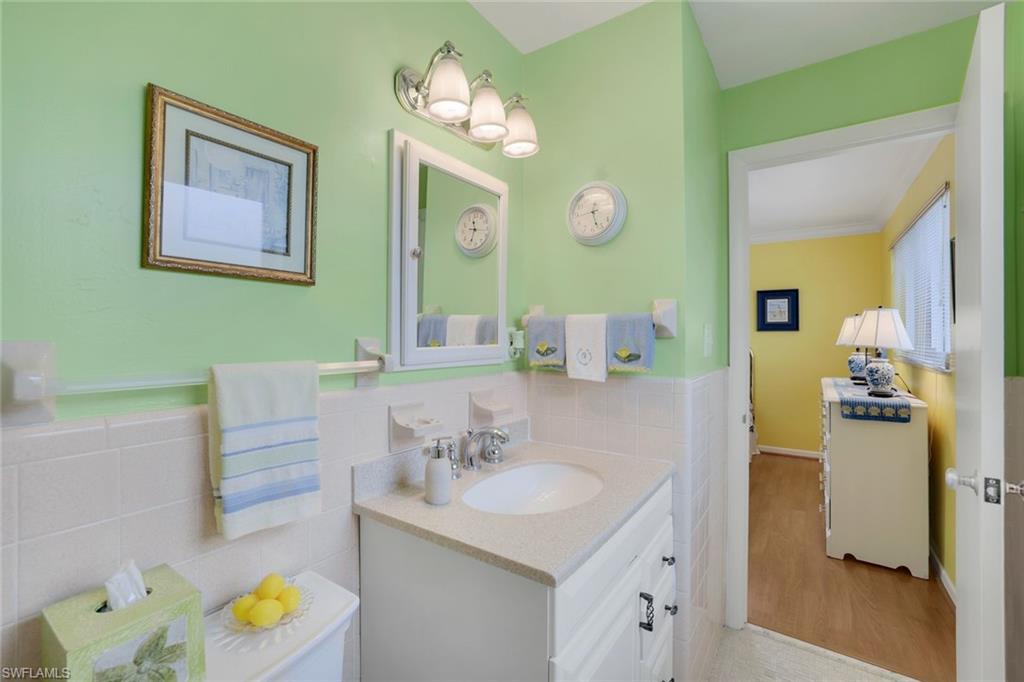 Bathroom featuring vanity, wood-type flooring, tile walls, and toilet