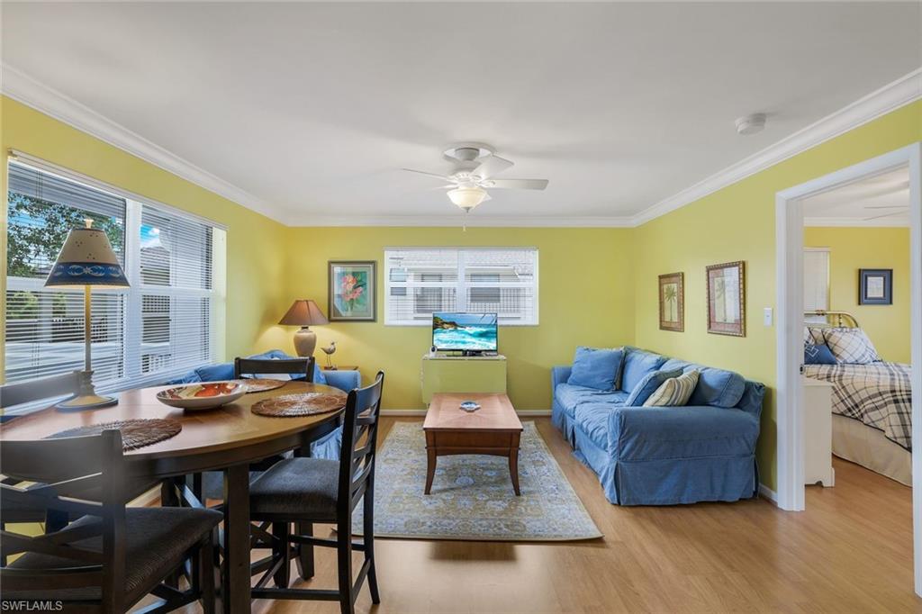 Living room with crown molding, ceiling fan, and light wood-type flooring