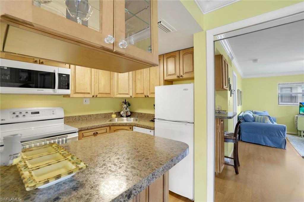 Kitchen featuring white appliances, ornamental molding, light hardwood / wood-style floors, and sink