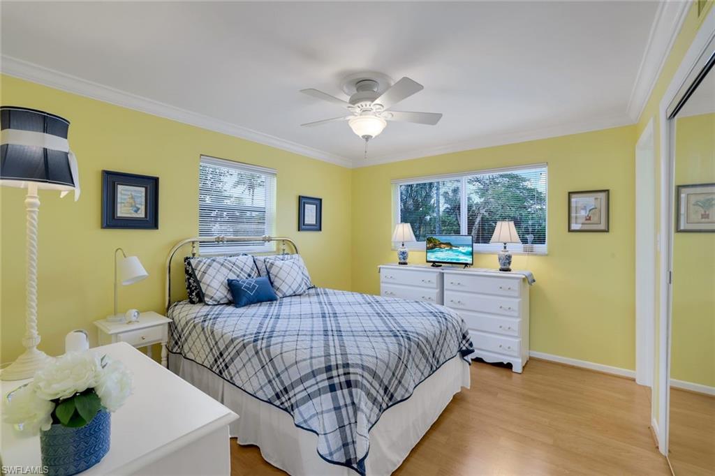 Bedroom with multiple windows, ornamental molding, ceiling fan, and light hardwood / wood-style floors
