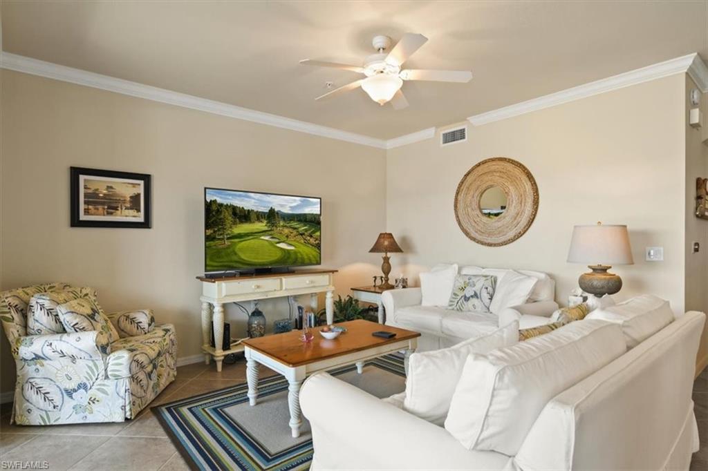 Tiled living area with crown molding and ceiling fan